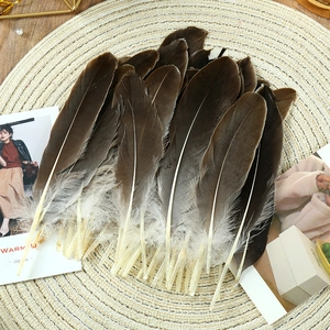 Detailed view of natural gradient goose feathers on a beige woven mat for DIY crafts
