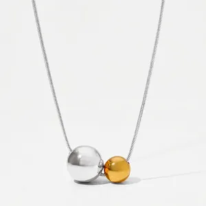 Detail of silver and gold dual-tone hollow spherical pendants on a sleek snake chain