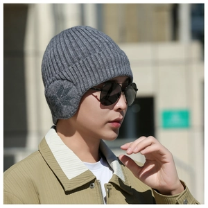Close-up of gray knit beanie featuring long ear flaps and dark gray maple leaf jacquard
