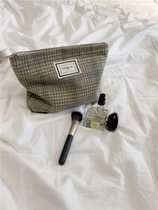 Macro detail of checkered wool toiletry bag with PLEASANT TIME label and zipper