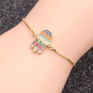 Détail du bracelet Hamsa doré avec zircons colorés et breloque mama sur un poignet
