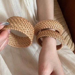 Gros plan détaillé de bracelets en rotin tressé à la main ton bois naturel sur le poignet