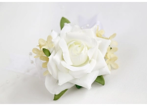 Détail de boutonnière rose blanche artificielle avec feuilles vertes et ruban de perles