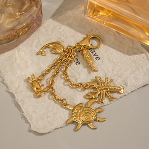 Detailed close-up of golden ocean-themed keychain featuring dolphin and lobster charms