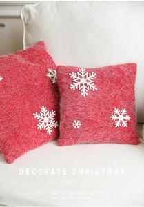Close-up of red and white Christmas snowflake pillows on a white sofa with plush texture