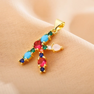 Macro shot of letter F pendant with multi-colored zircons in a gold-plated setting