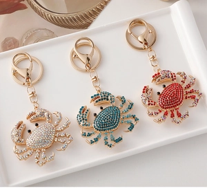 Close-up of sparkling colorful rhinestone crab keychains with lobster clasps on a white tray