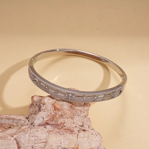 Close-up of silver hollow floral bangle with cubic zirconia on natural stone base