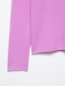 Detailed close-up of ribbed cuffs and hem on a soft mauve knit cashmere sweater