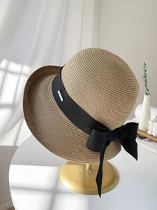 Détail d'un chapeau de paille beige avec ruban noir et texture tressée de qualité