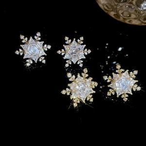 Macro shot of silver snowflake earrings with cubic zirconia crystals on black background