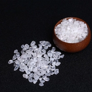 Macro shot of clear quartz crystal chips on black background with a ceramic bowl