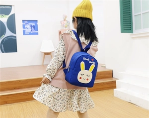 Rear view of a child wearing the blue Small Rabbit canvas backpack in a natural setting