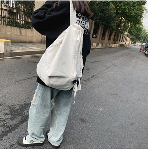 Street style view of a white canvas backpack with adjustable straps and drawstring closure
