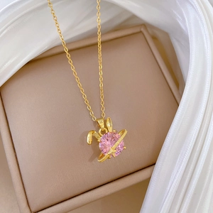 Detailed close-up of a pink rabbit necklace with a gold chain on soft silk fabric