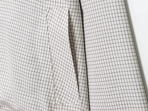 Détail d'un trench court avec tissu à carreaux gris et couture de poche latérale