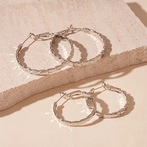 Detailed view of silver hoop earrings with textured bamboo patterns on a stone block