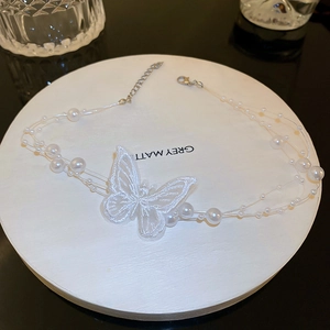 Détail du collier ras du cou papillon en dentelle blanche avec perles multicouches sur noir