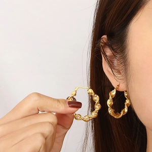 Gold twisted rope hoop earrings with sparkling zirconia stones shown on model
