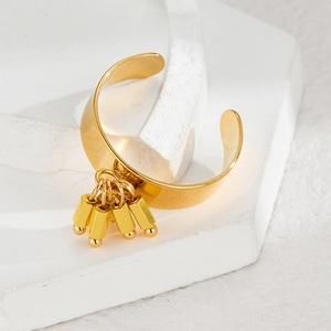 Polished gold wide band ring featuring hanging cylinder tassel charms on white surface