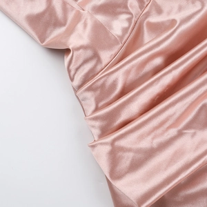 Detailed macro shot of pink satin dress fabric showing delicate pleats and high-quality texture