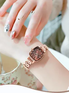 Detail of rose gold square watch with brown sunray dial and crystal accents on wrist