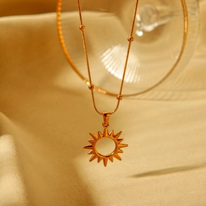 18K gold plated stainless steel sun pendant necklace on elegant silk background