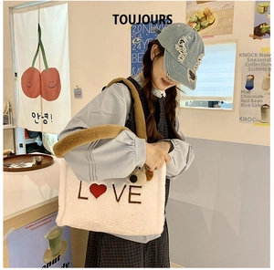 Close-up of plush cream tote bag with LOVE embroidery and a cute brown puppy charm