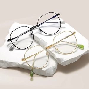 Square blue light blocking glasses with black and gold metal frames on white stone