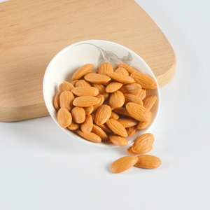 Realistic PVC almond models displayed in a white ceramic bowl on a wooden board