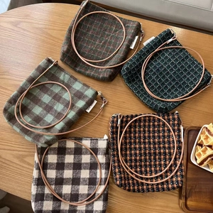 Flat lay of vintage plaid wool crossbody bags in five colors on a rustic wooden table