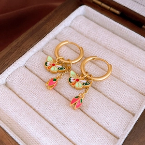 Detail of matte gold butterfly flower earrings with enamel on a velvet jewelry tray