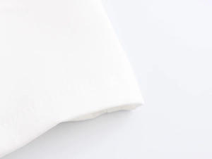 Macro shot of fine plain weave white fabric and detailed stitching on the elegant trousers