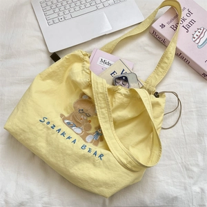 Detail of cute bear embroidery and drawstring closure on a yellow canvas tote bag