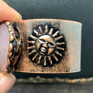 Makrodetail des Bronze-Sonnenreliefs und Rosaquarz-Steins an böhmischem breitem Armreif