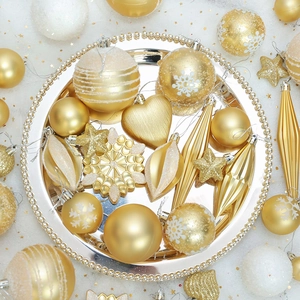 Golden and white assorted Christmas tree ornaments in varied geometric shapes on a silver tray