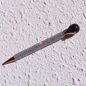 Close-up of sparkling colorful rhinestones on a rose gold metal ballpoint pen
