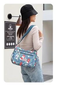 Outdoor shot of a floral shoulder bag with adjustable strap and multiple zip pockets