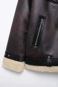 Detail of faux shearling cuffs and adjustable leather buckles on a brown jacket
