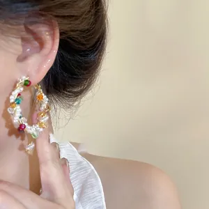 Détail de grandes créoles avec perles multicolores et fil doré portées par un mannequin