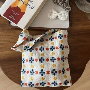 Vintage floral embroidery canvas underarm bag on a dark wood background with books