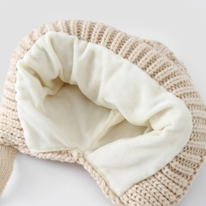 Detailed close-up of warm beige crochet knit hat with soft white fleece lining texture