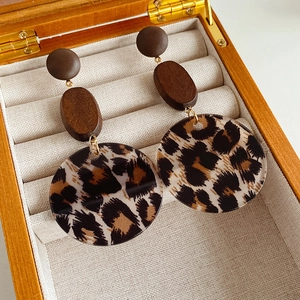 Detail of vintage leopard print resin earrings with dark brown wood beads on beige velvet