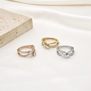 Close-up of tricolor crisscross stainless steel rings with sparkling crystals on silk