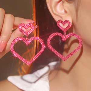 Macro detail of luxury sparkling double pink heart earrings with crystal rhinestones