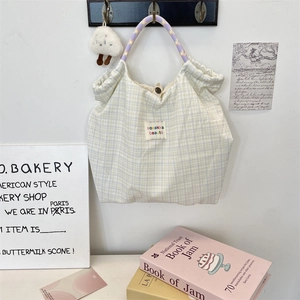 Détail du sac cabas en toile à carreaux jaunes avec anses violettes et logo cousu