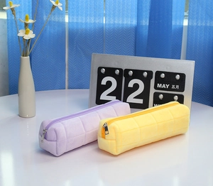 Close-up of quilted plush pencil case showing soft purple and yellow checkered textures