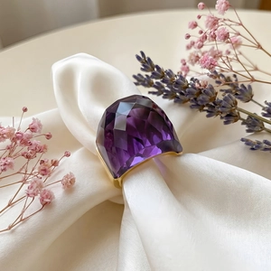 Close-up of a large faceted purple crystal ring on white silk with dried lavender flowers