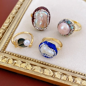 Detail of vintage gold-plated rings with baroque pearls and rhinestones on a gold tray