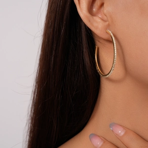 Macro view of gold-plated geometric hoop earrings with sparkling white cubic zirconia